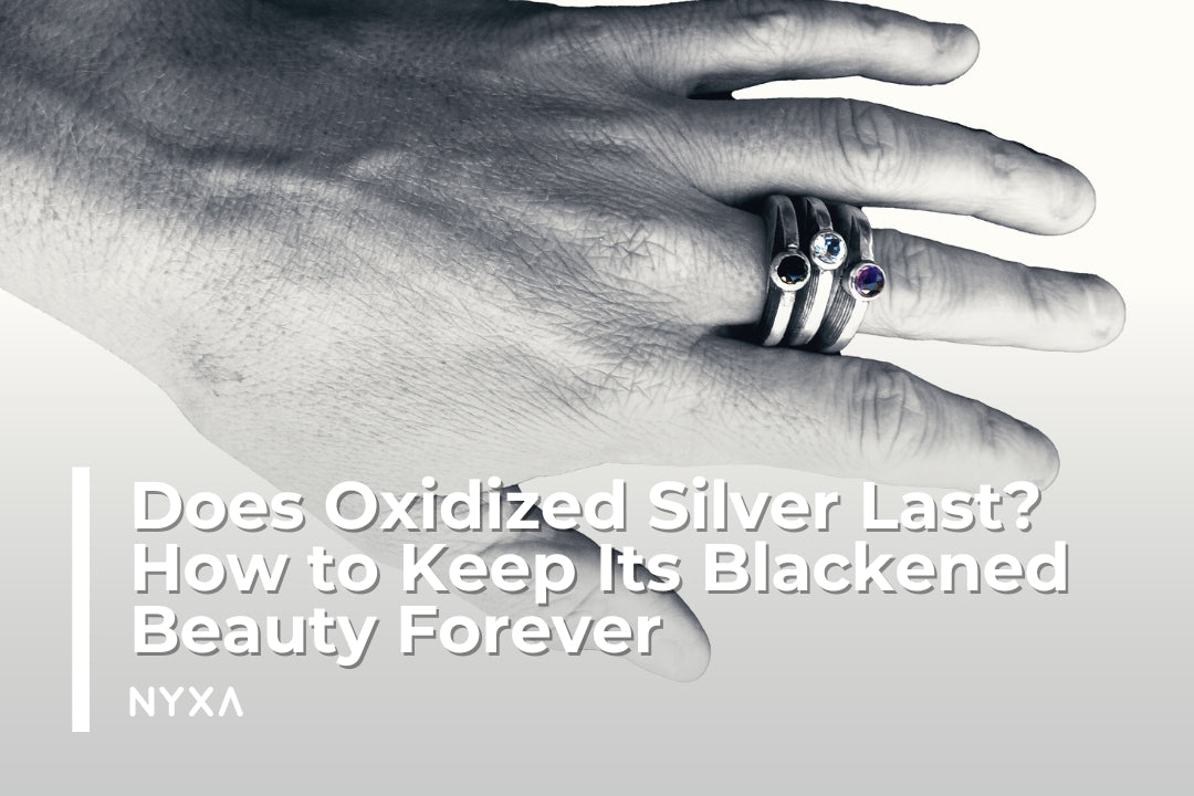 Hand wearing oxidized silver rings with gemstones, showcasing a blackened silver patina.