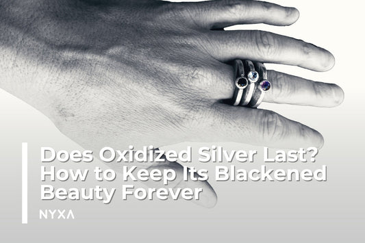 Hand wearing oxidized silver rings with gemstones, showcasing a blackened silver patina.